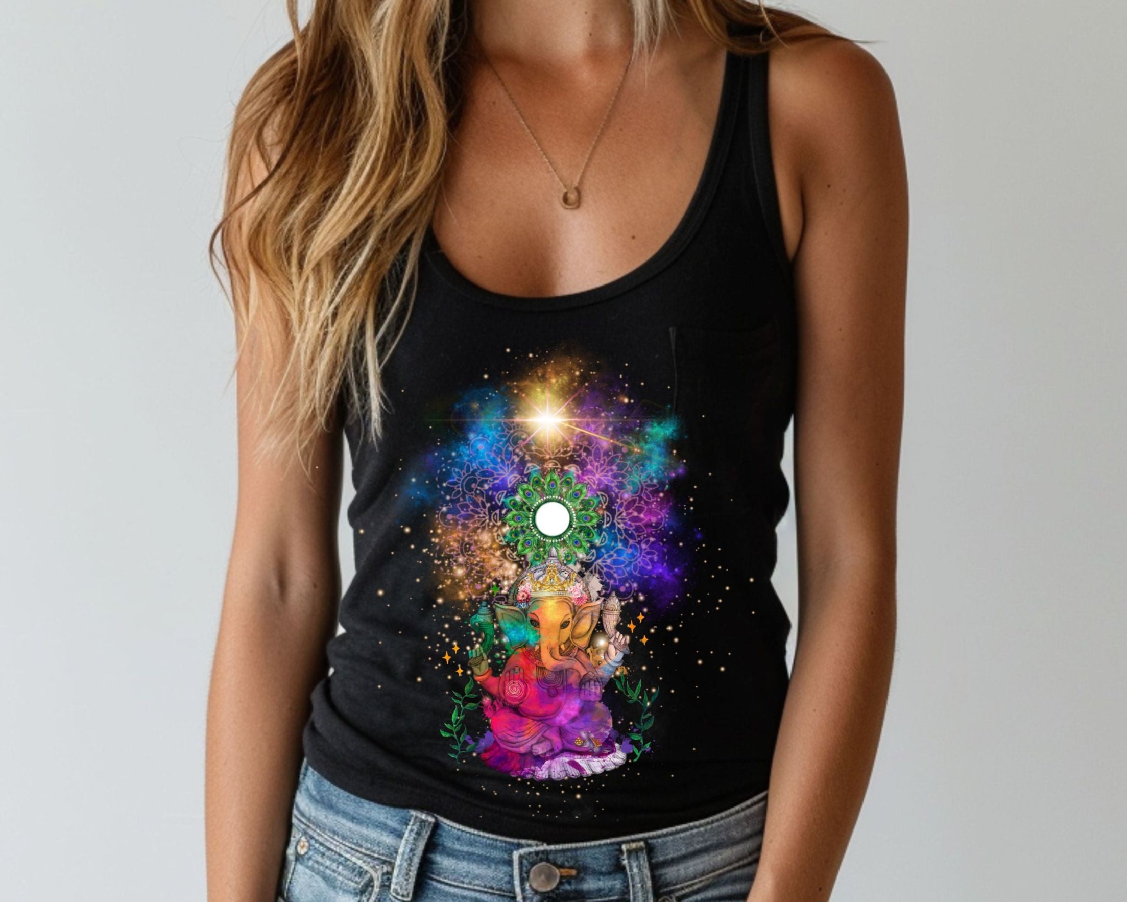 Farbenfrohes ganesha Tank Top in schwarz, getragen von einer jungen Frau mit blonden Haaren. Der Elefantengott ist in der Mitte des Tops abgeildet, hinter ihm sind bunte Lichter, die von Sternen umgeben sind und wie farbige Galaxien wirken. Über Ganesha befindet sich ein weißer Spiegel, kreirund und umgeben von einem grünen Mandala.